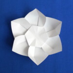 Photograph of origami pinwheel flower. It has six petals and a hexagonal center.